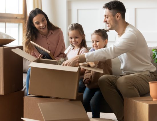 Family with young children unpacking moving boxes together in their new home