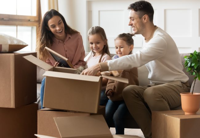 Family with young children unpacking moving boxes together in their new home