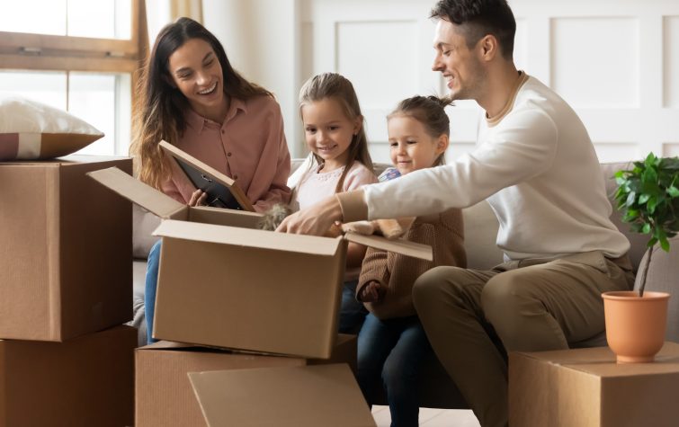 Family with young children unpacking moving boxes together in their new home