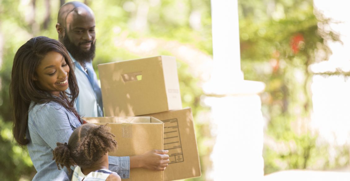 Family carrying boxes into their new home during a summer relocation move