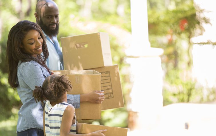 Family carrying boxes into their new home during a summer relocation move