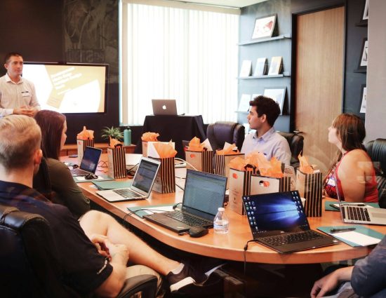 HR team in a conference room reviewing a flexible relocation benefits program presentation with laptops and materials on the table