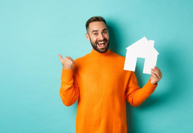 Employee holding a house cutout representing a guaranteed buyout during relocation