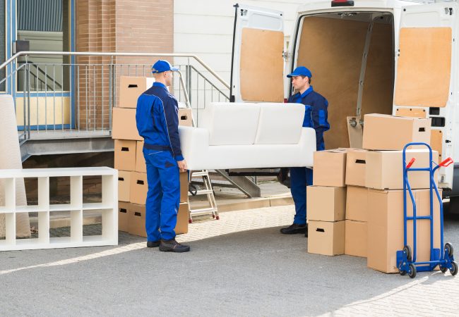Movers carrying sofa outside truck on street