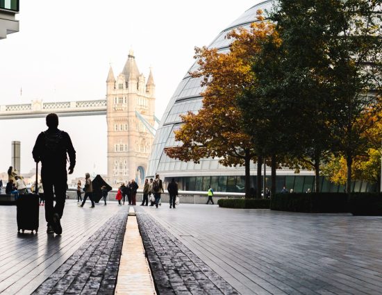 Traveler with luggage walking near Tower Bridge in London, a leading destination for global talent