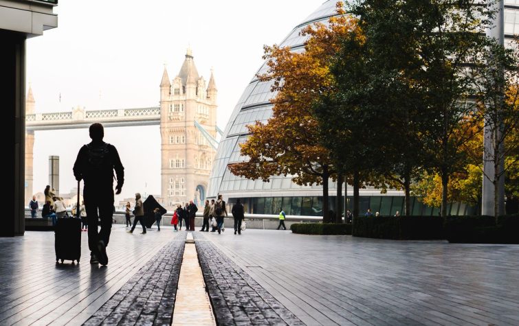 Traveler with luggage walking near Tower Bridge in London, a leading destination for global talent
