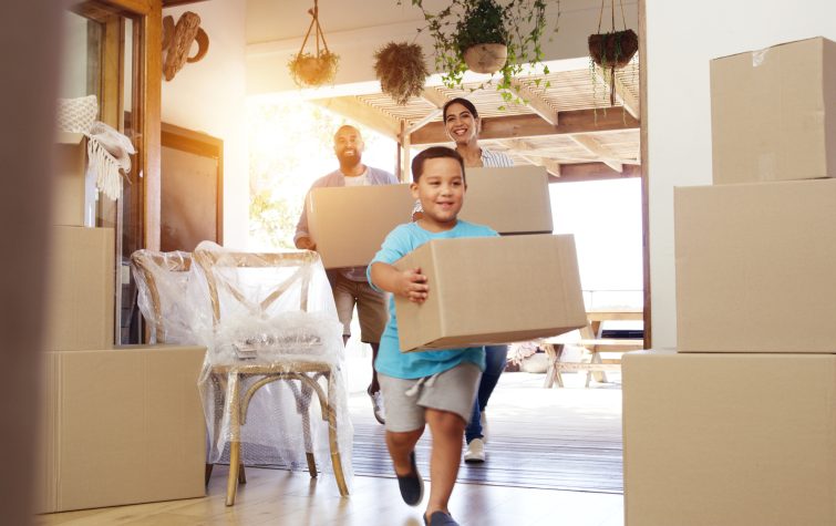 Family carrying moving boxes into their new home during an employee relocation