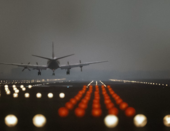 Commercial airplane landing at night representing international assignment travel and the AI in global mobility technology that supports program planning