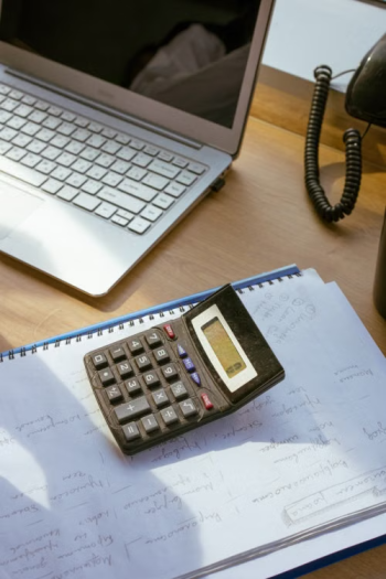 Calculator on handwritten notes next to a laptop representing the detailed relocation cost estimates HR teams build for mobility budget planning