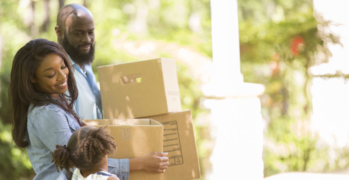 Family carrying boxes into their new home during a summer relocation move