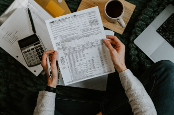Person reviewing IRS Form 1040 with a calculator representing the employment tax and payroll review required for global mobility compliance