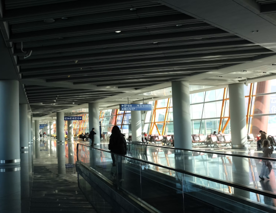Traveler on moving walkway in an international airport terminal representing the immigration and global mobility compliance requirements that begin before an employee boards a flight