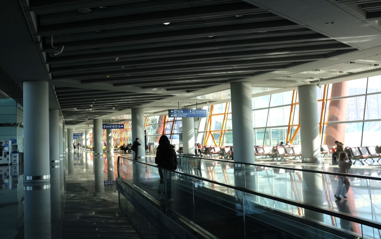 Traveler on moving walkway in an international airport terminal representing the immigration and global mobility compliance requirements that begin before an employee boards a flight