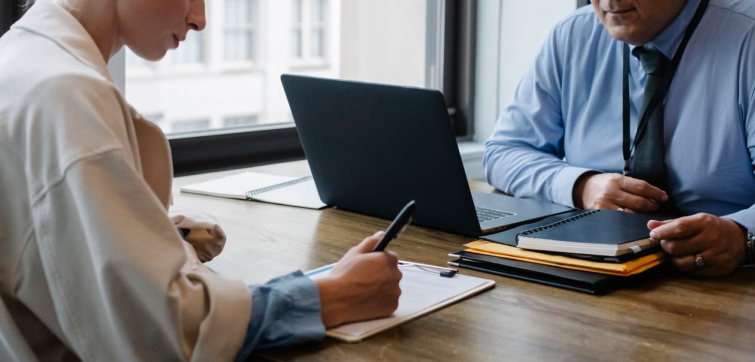 Two professionals reviewing documents at a desk representing the legal and HR review required before drafting or enforcing a relocation repayment agreement